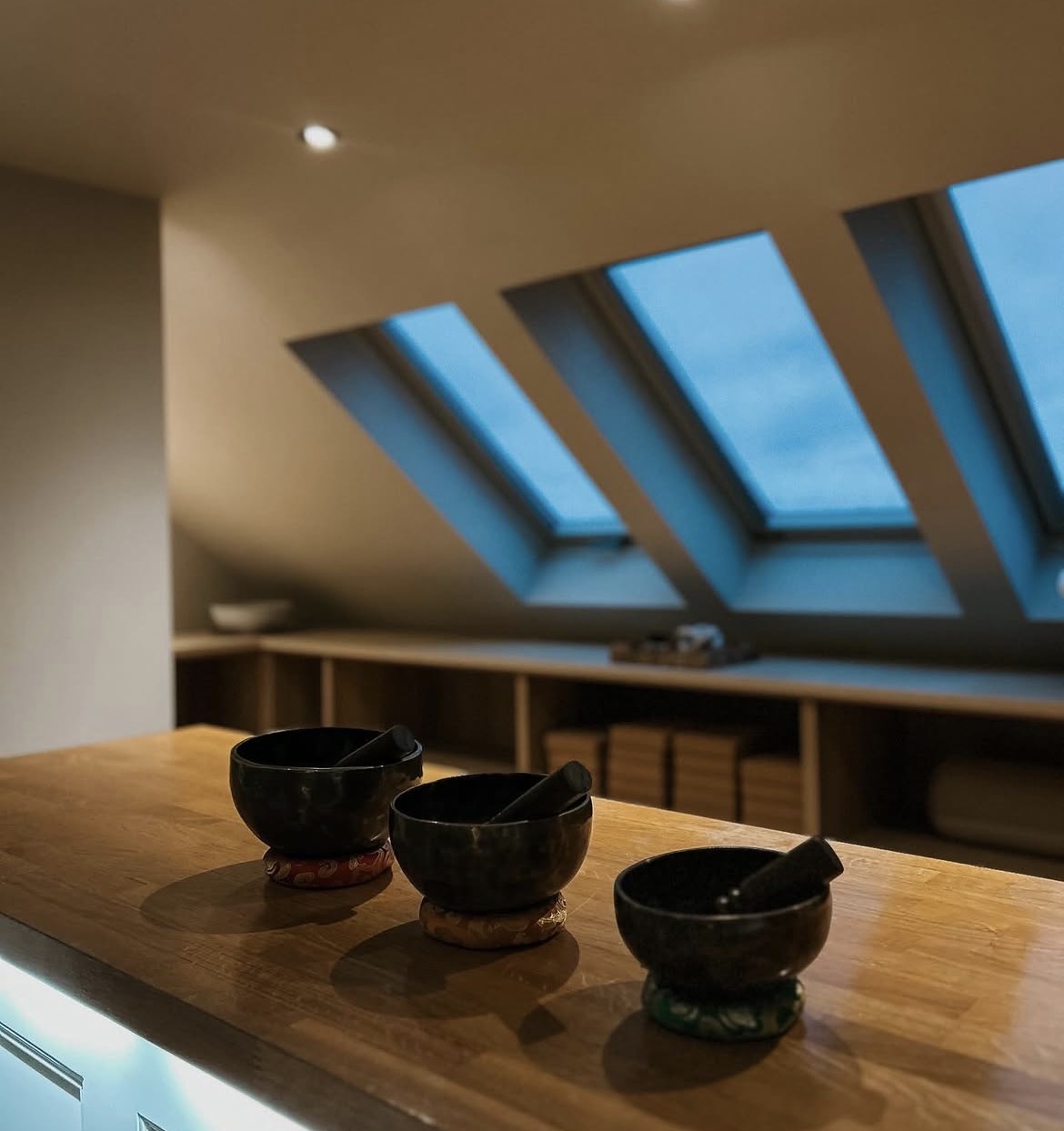 Singing bowls on the studio's wooden counter with skylights above